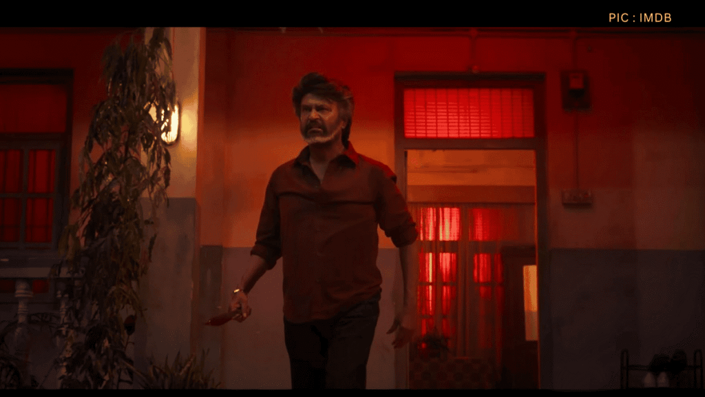 Rajinikanth as Deva walking confidently with a weapon in hand, amidst dramatic red lighting, from the film Coolie (2025).