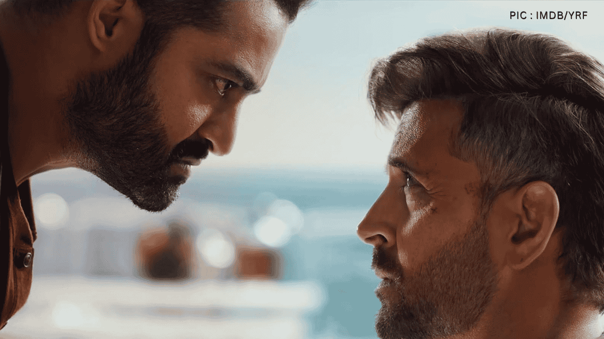 NTR JR and Hrithik face each other closely in an intense scene, with modern cityscape in the background.