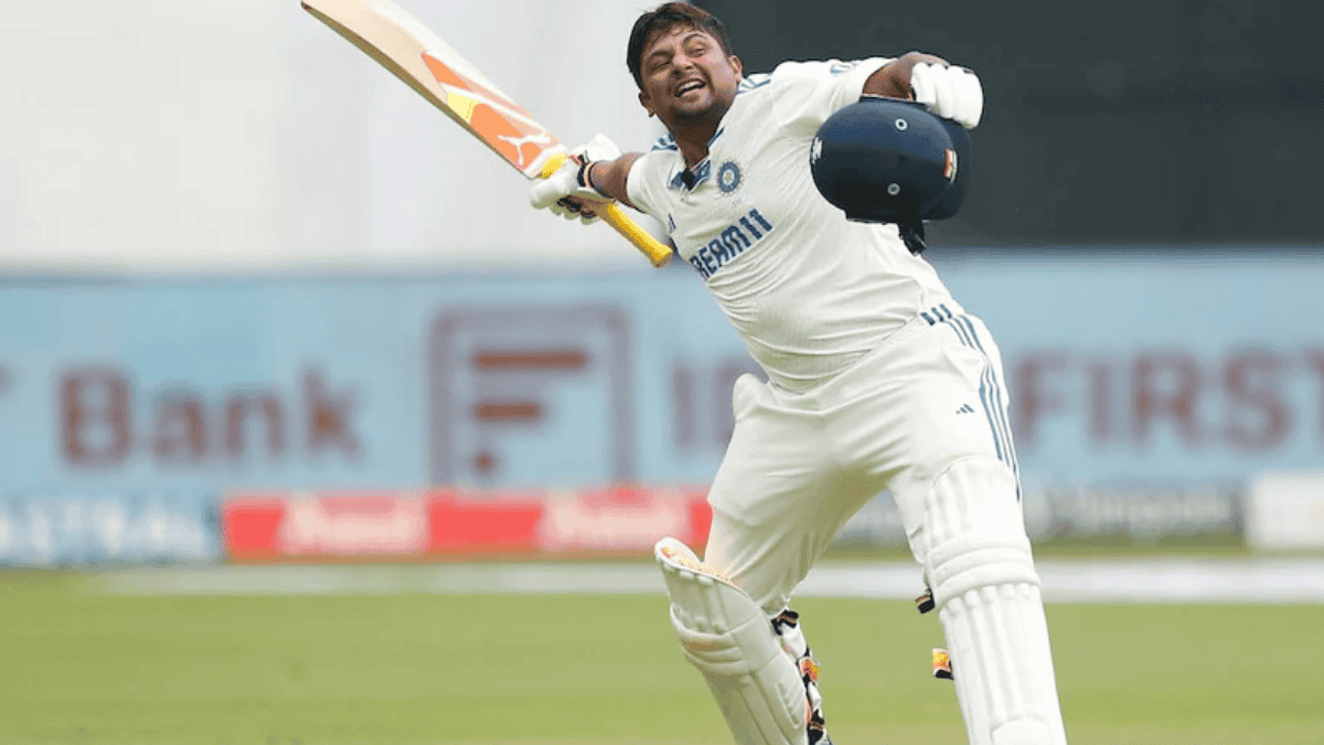 Indian cricketer in full action playing a shot during a Test match, wearing white cricket kit with bat extended and helmet in hand.