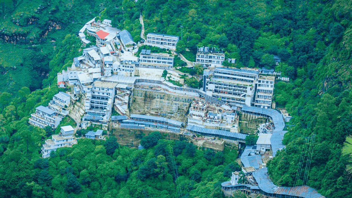 वैष्णो देवी मंदिर परिसर का हवाई दृश्य, हरियाली से घिरे पहाड़ी क्षेत्र में स्थित भवनों और मार्गों के साथ